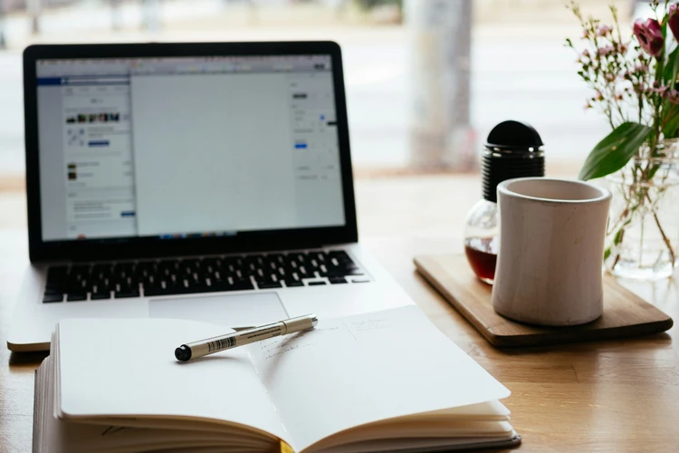 Laptop, journal, pen and coffee on a table